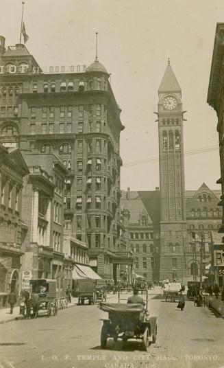 Black and white photograph of a busy city street with a large public building with a clock towe ...