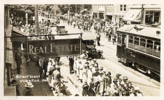Black and white photograph of a large crowd on a busy city street. Possibly a pararde.