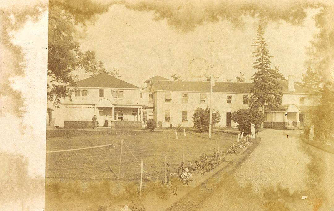 Black and white photograph of a several large buildings on manicured grounds.