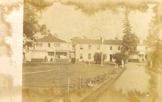 Black and white photograph of a several large buildings on manicured grounds.