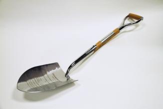 A silver spade with wood and metal handle.