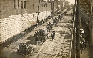 Picture of large funeral procession on a street. 