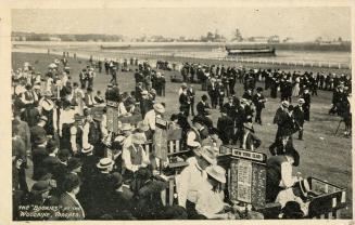 Picture of people lined up at bookies wickets at a race track. 