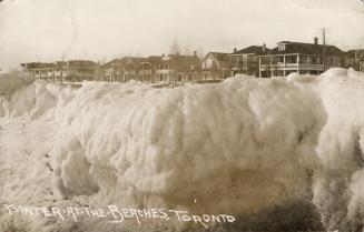 Picture of ice formations on the beach and houses in the background. 