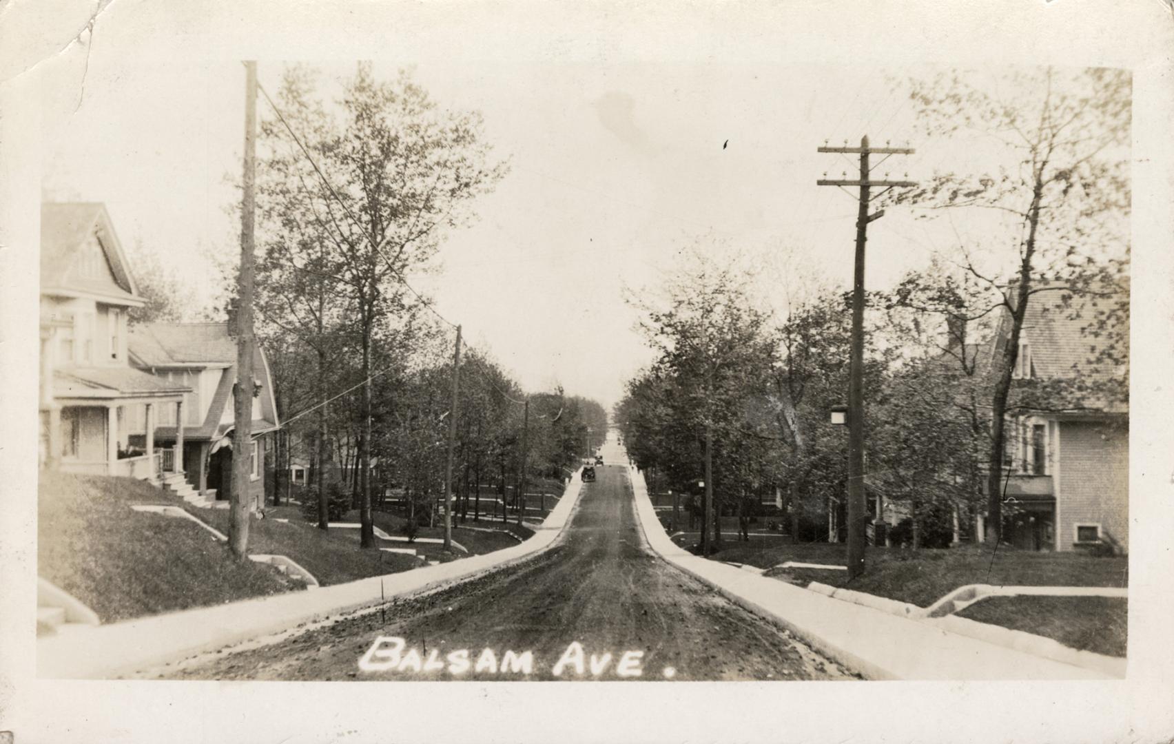 Picture of dirt street with sidewalks and houses on both sides. 