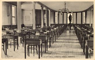 Black and white photograph of rows of desk lined up in a large room with pillars.