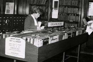A woman browses records in a music library. 