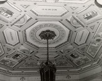 A photograph of a chandelier and the ceiling it is hanging from. The ceiling has an octagon-sha ...