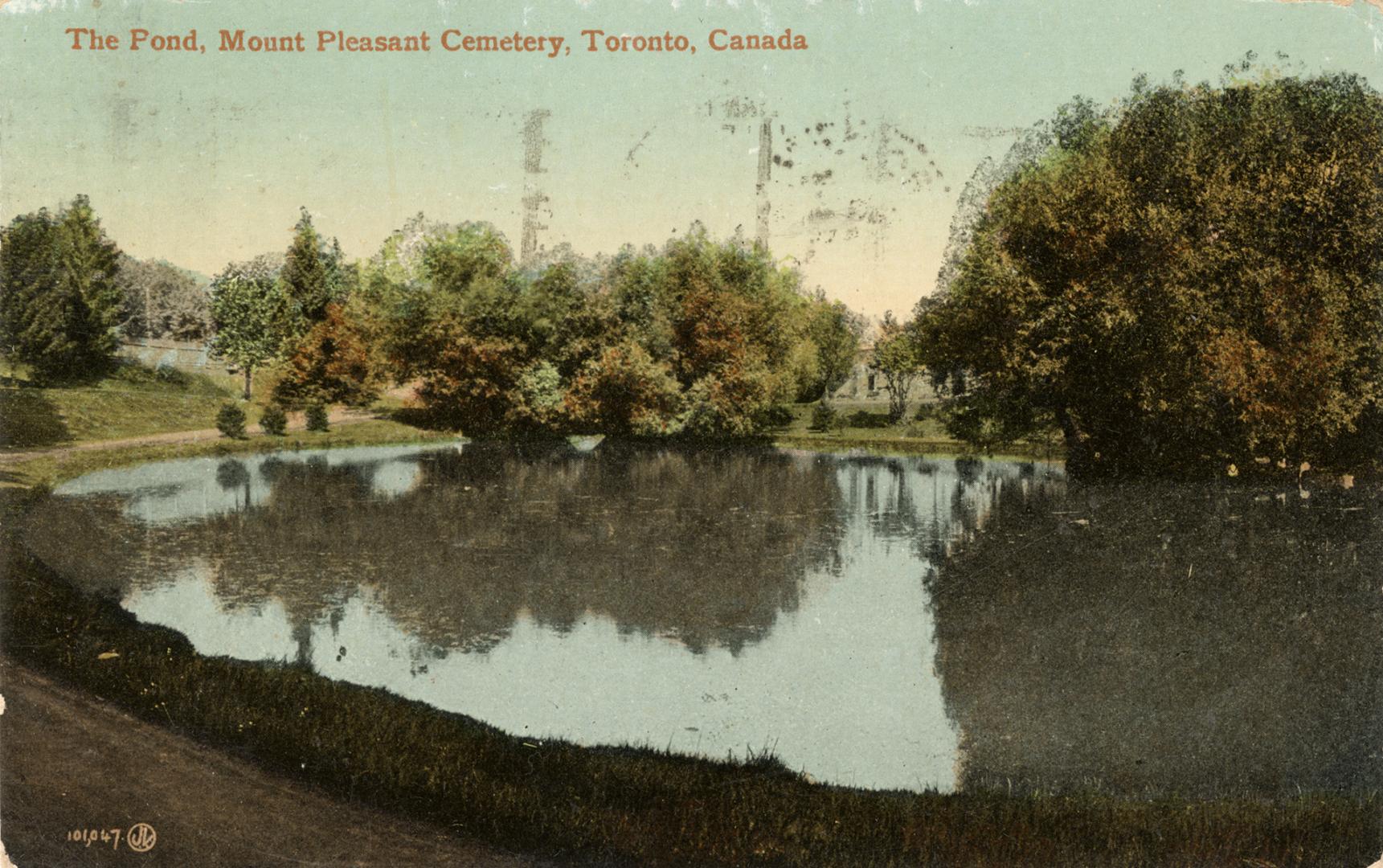Colour postcard of a pond surrounded by trees. The caption on the top front states, "The Pond,  ...
