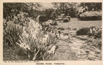 Black and white postcard of a park with flowers. The caption on the bottom front states, "Moore ...