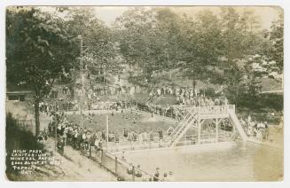 Black and white photograph of people swimming in a large pool in a wooded area.