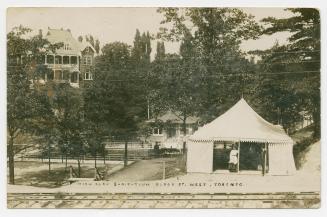Black and white photograph of a tent beside a large swimming pool.