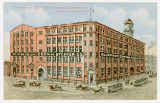 Picture of a large brick factory building on a street corner. 