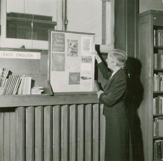 Picture of librarian standing at a display board. 