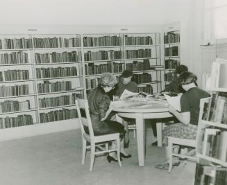 Picture of four people seated at a table in a library. 