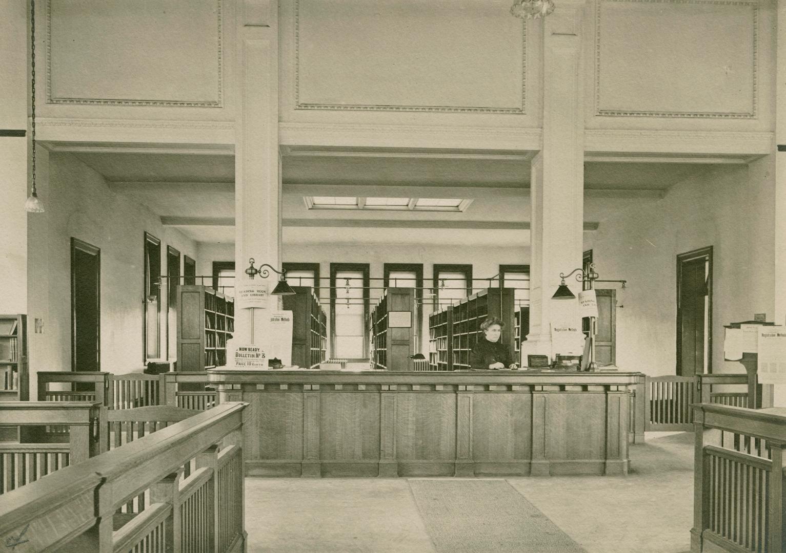 Interior of a library with wooden desk, pillars and bookshelves. 