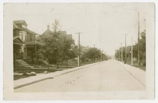 Black and white picture of a street in a residential area.