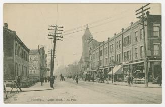 Picture of street scene with buildings on both sides, hydro poles and people walking. 