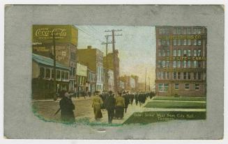 Picture of a street with buildings on both sides. Silver border around image. 