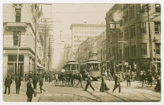 Black and white photograph of a busy city intersection with people, streetcars and horse drawn  ...