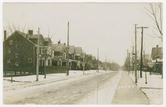 Black and white photograph of small town street with houses on each side of it.