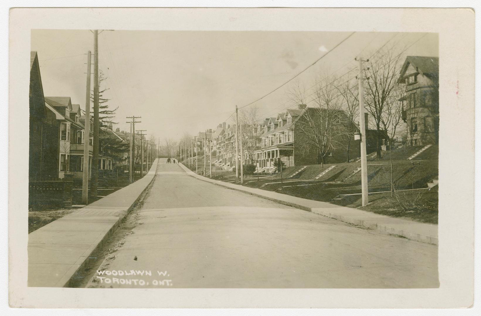 Black and white photograph of small town street with houses on each side of it.