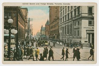 Picture of a street intersection with stores, streetcars and people walking. 