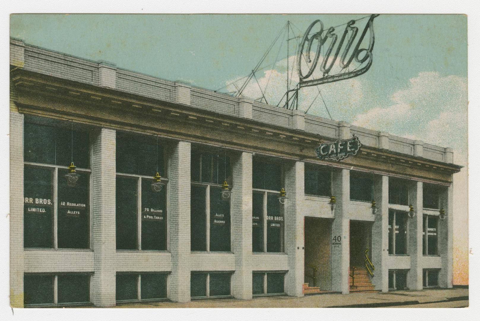 Picture of a cafe with sign on top of building. 