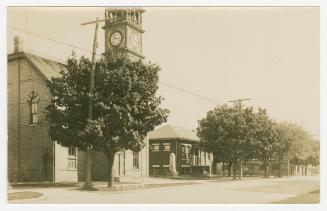 Picture of treed street with town hall and library. 