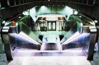A photograph of a staircase leading down one floor to the entrance of a subway station. The ent ...