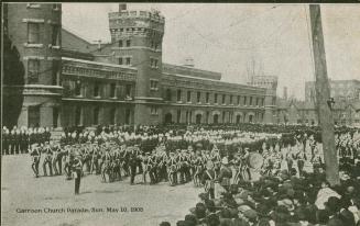 Black and white photograph of soldiers in dress uniform on parade in front of a huge, castle-li ...