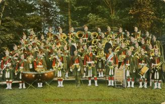 Colorized photograph of a large marching band in Scottish dress posing in a park