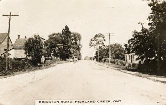 Picture of a dirt road with houses on each side and horse and buggy in distance. 