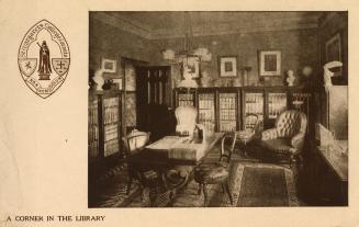 Picture of the interior of a library room with border and school crest on right side of card. 