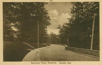 Sepia-toned postcard depicting a curvy road with trees and a house partially visible on the lef ...