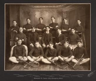 A photograph of a lacrosse team, with sixteen young men sitting and standing in a studio facing ...