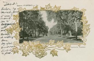 Black photograph of a city street bordered by large houses and trees, with a golden maple leaf  ...
