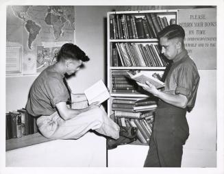 Photo of two men reading in a library. 