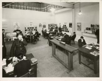 Photo of men reading in a library. 