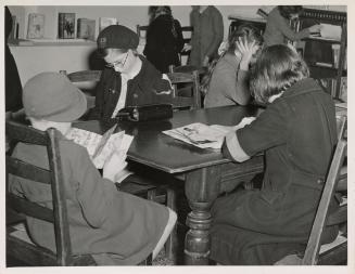 Photo of girls reading at a table in a library.