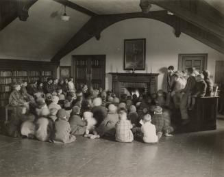 Photo of children gathered around a fireplace for story time. 
