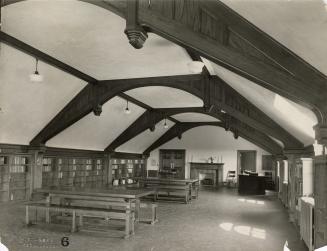 Photo of large library room with wooden arched ceiling and wooden tables, fireplace built in sh ...