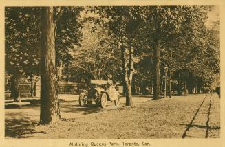 Picture of woman driving a car along a road in a park. 