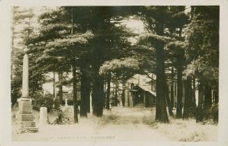 Black and white photograph of a country church and graveyard in a forest.
