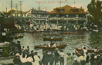 Colorized photograph of a huge crowd of people watching people in canoes in front of a large bu ...