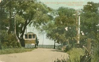 Colorized photograph of a street car stopped in front of a lake.