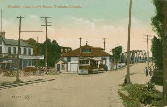 Colorized photograph of a streetcar running along a road in front of cottages.