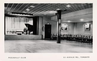 Black and white photo postcard depicting a large room with chairs off to the side and a grand p ...