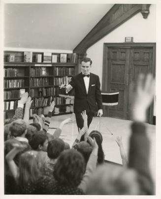 Photo of magician performing a trick in front of group of children. 
