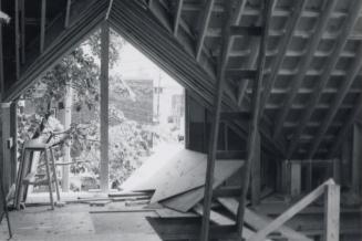 Photo of interior of room with peaked roof under construction. 